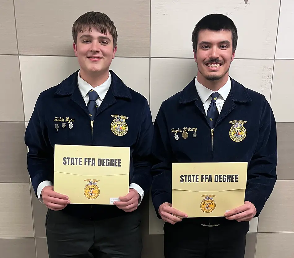 Two members of the Pettisville FFA stand side by side against a wall displaying their State FFA Degrees, dressed in their official FFA uniforms.